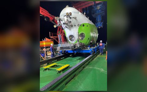 夜间停靠在母船甲板上的白绿相间的“奋斗者”号潜水器