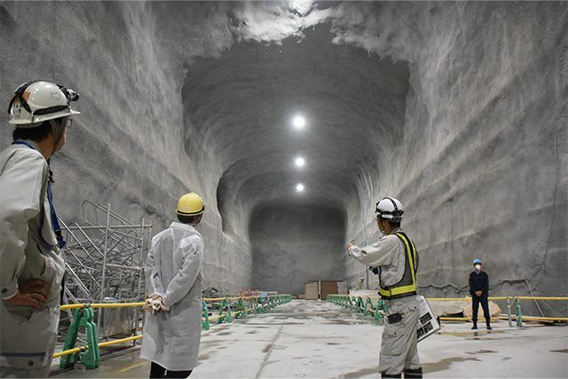 戴着安全帽的官员在Hyper-Kamiokande建设中的巨大岩石洞室内进行视察