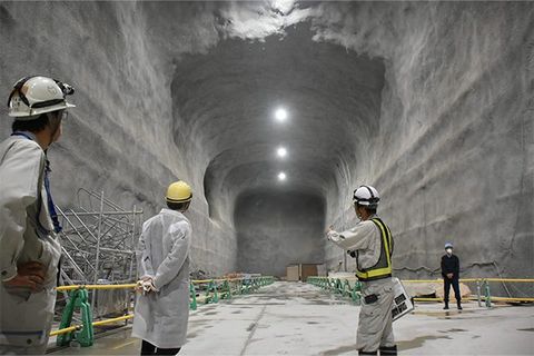 戴着安全帽的官员在Hyper-Kamiokande建设中的巨大岩石洞室内进行视察