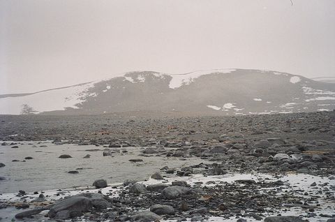 南极难言岛上布满岩石的海岸线与积雪斑驳的丘陵