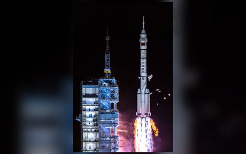 长征二号F火箭在酒泉发射塔架旁夜间升空